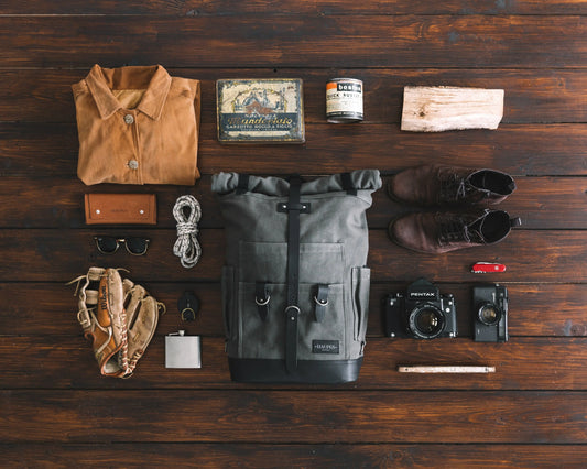 background of wood in the center a travel backpack and items normally pack in travel